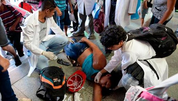 Personal médico asiste a una mujer lesionada durante el choque entre policías y manifestantes en la Estación Central de trenes, metro y autobuses, de Rio de Janeiro. (Foto: afp)