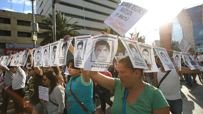 Los familiares de los jóvenes desaparecidos marchan con fotos de sus rostros (Foto: EFE)
