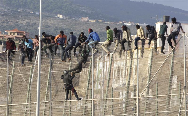 Un centenar de inmigrantes permanecen encaramados en la valla fronteriza entre Melilla y Marruecos. (Foto: EFE)