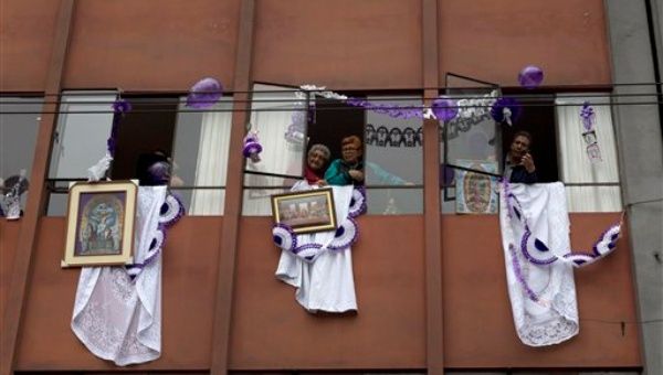 Las personas que viven en edificios de apartamentos a lo largo del camino observaban desde ventanas decoradas con motivos púrpura y blanco. (Foto: AP)