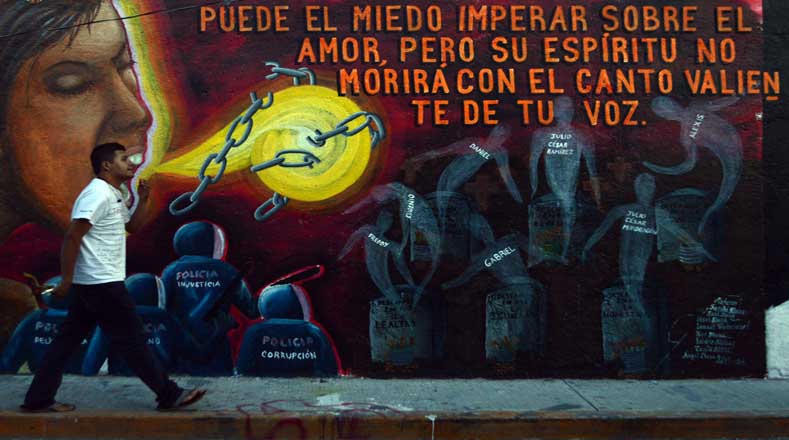 Un hombre camina frente a mural en la escuela de Ayotzinapa en honor a los 43 normalistas (Foto: EFE)