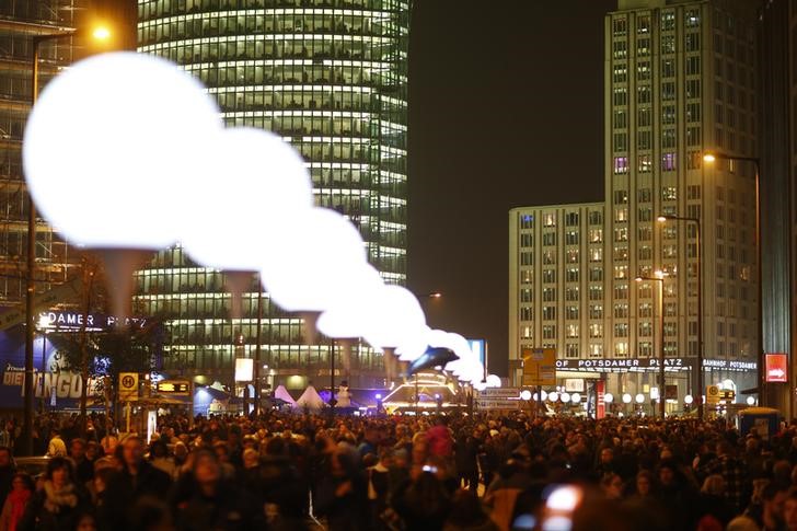 La gente camina bajo los globos iluminados que representan al Muro de Berlín en Potsdamer Platz