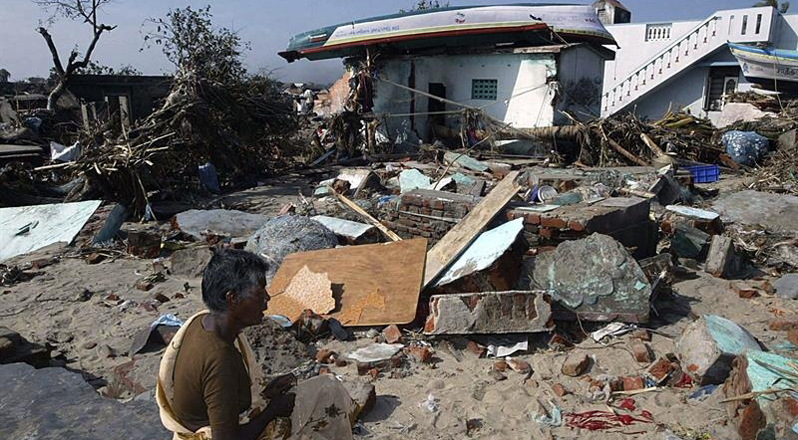 Una persona permanece sentada entre los escombros mientras observa lo que quedó de su casa en Nagapattinam, Tamil Nadu (India) hace 10 años.