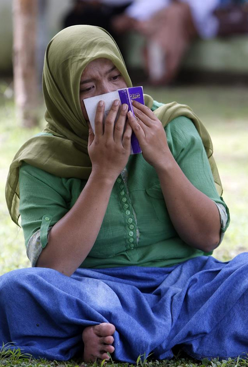 Una mujer llora y reza en una fosa común en Banda Aceh (Indonesia).