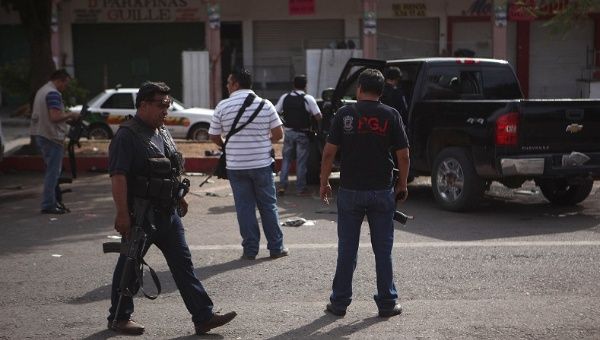 Plainclothes police stand next to a bullet-riddled pickup truck after a shooting between federal forces and armed civilians in the town of Apatzingan, Michoacan Jan. 6, 2015.