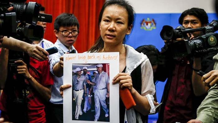 Una mujer sostiene la fotografía de su esposo que desapareció en el vuelo MH370.