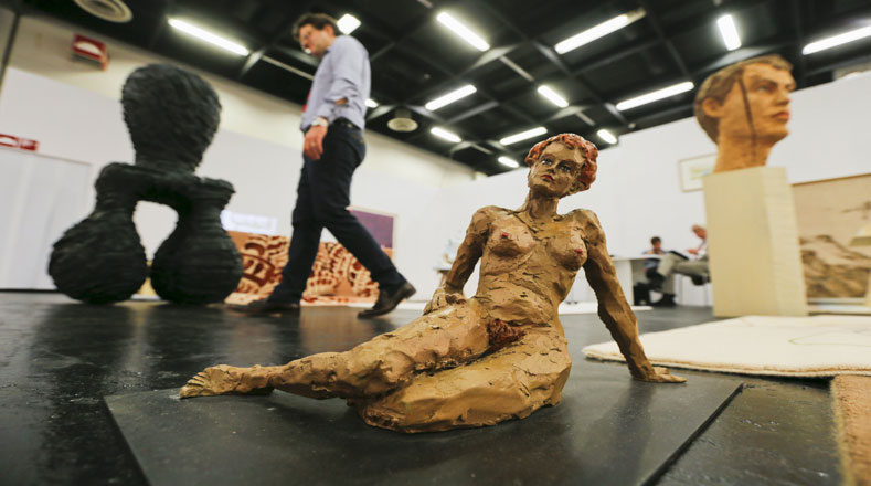 Un galerista belga pasa junto a la escultura de color bronce de nombre "mentir mujer " del escultor alemán Stephan Balkenhol en la Art Cologne 2015 en Alemania.