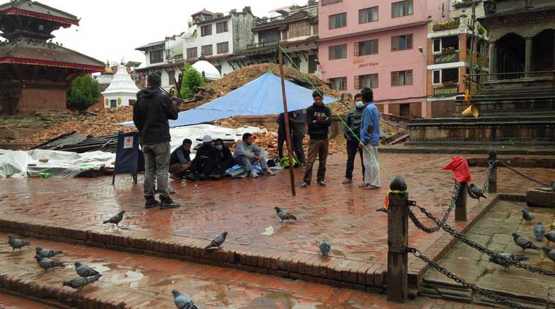 Los vigilantes del centro cultural de #lalitpur se protegen de la lluvia entre los templos destruidos