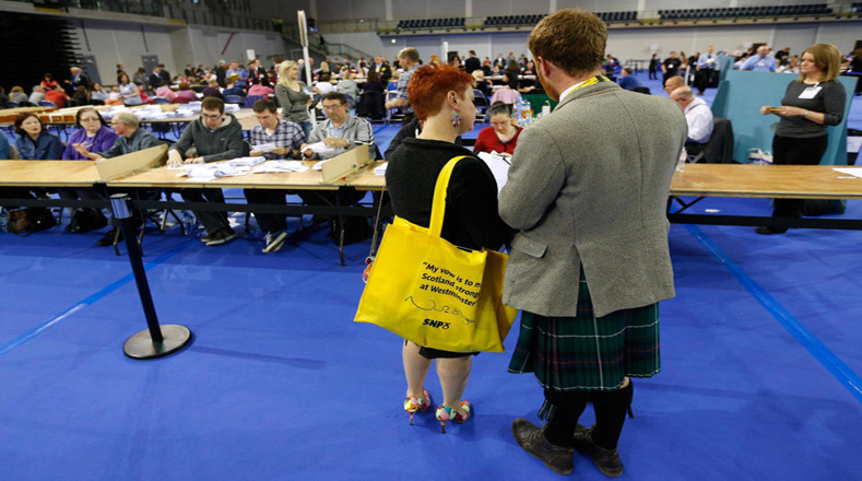 Trabajadores del SNP observan el recuento de votos en Glasgow tras el cierre de los colegios.