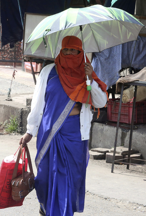 Las personas con paraguas intentan protegerse del calor en Bhopal, India.