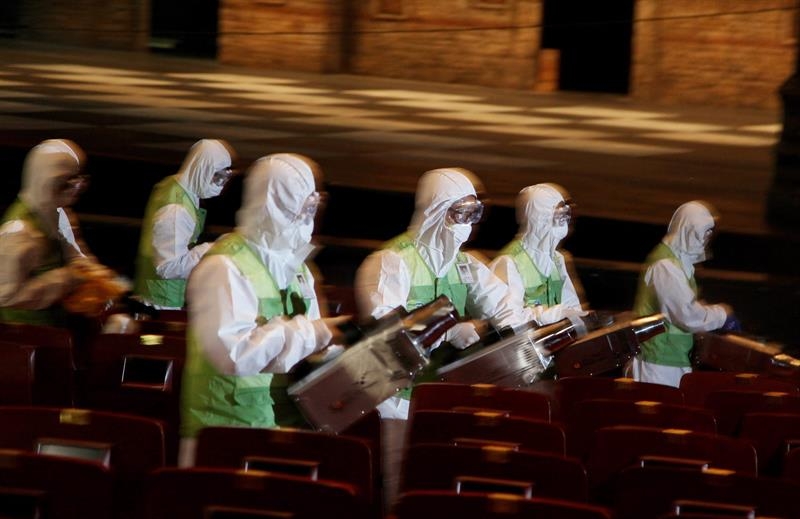 Miembros de una brigada de salud fumigan un teatro para evitar la propagación del virus.