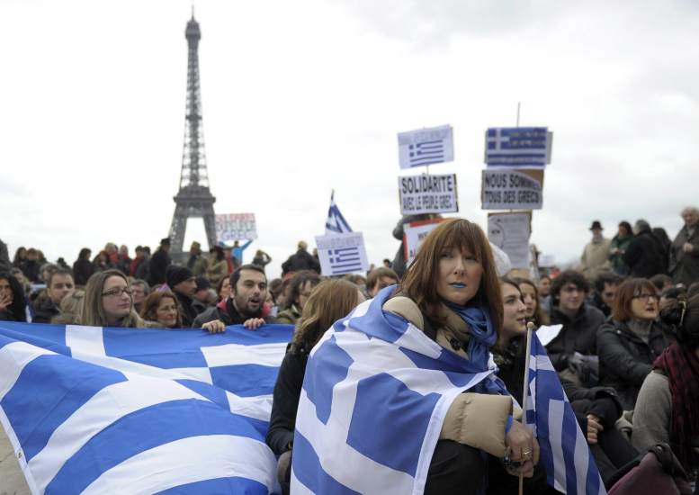 Manifestantes con banderas griegas protestan en una marcha solidaria contra las medidas de austeridad de Grecia en frente de la Torre Eiffel en París, Francia.