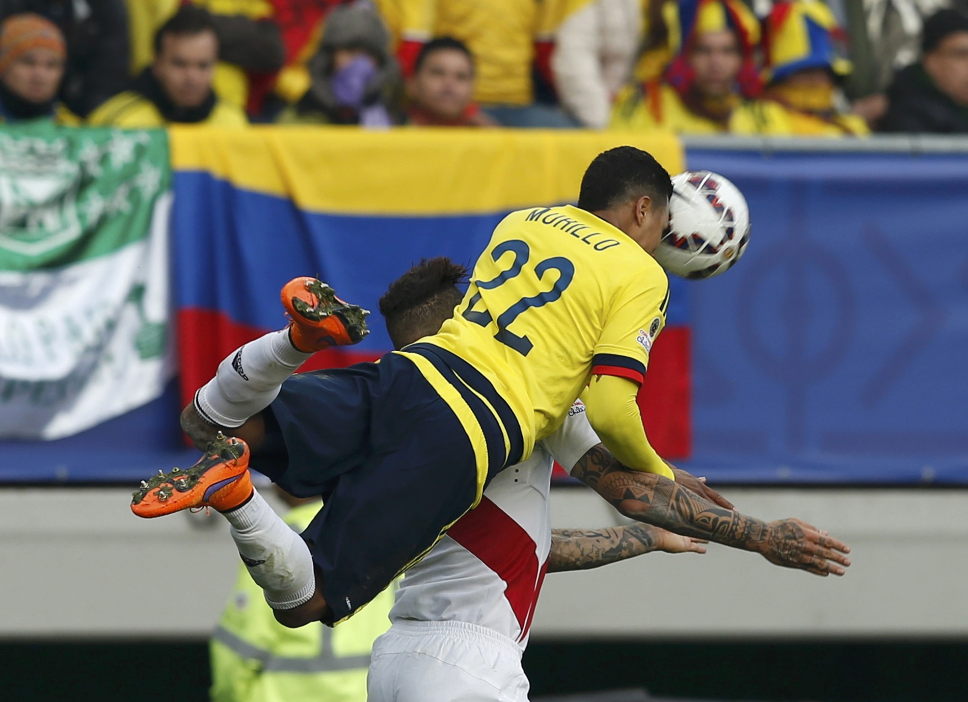 Jeison Murillo cabecea la pelota mientras salta sobre Paolo Guerrero de Perú.