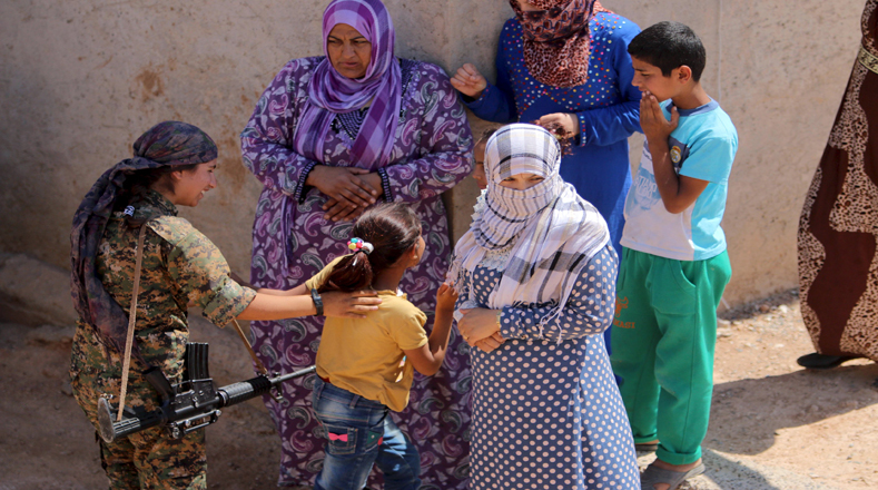 Una combatiente kurda se encuentra con los residentes de las aldeas cercanas a la ciudad de Tal Abyad (Siria) para expresar su apoyo ante los ataques perpetrados por el EI. 