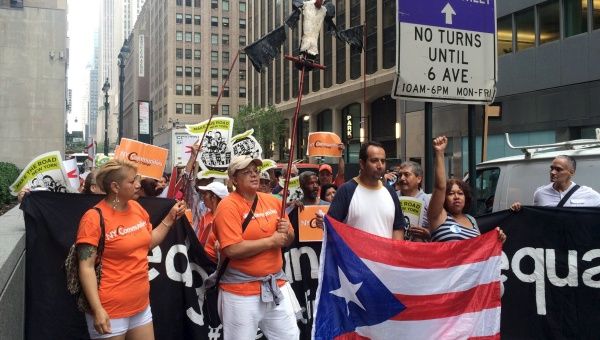 Protesters carrying a vulture puppet and chanting in Spanish marched outside the Park Avenue offices of a major holder of Puerto Rico
