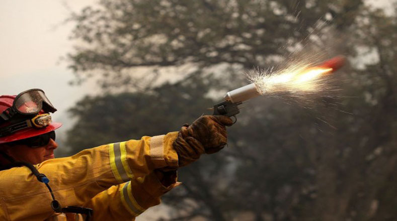 Un bombero quema la hierba seca durante una operación para extinguir el fuego en California.