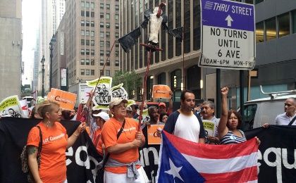 Protesters carry a vulture puppet and chant in Spanish outside the Park Avenue offices of a major holder of Puerto Rico