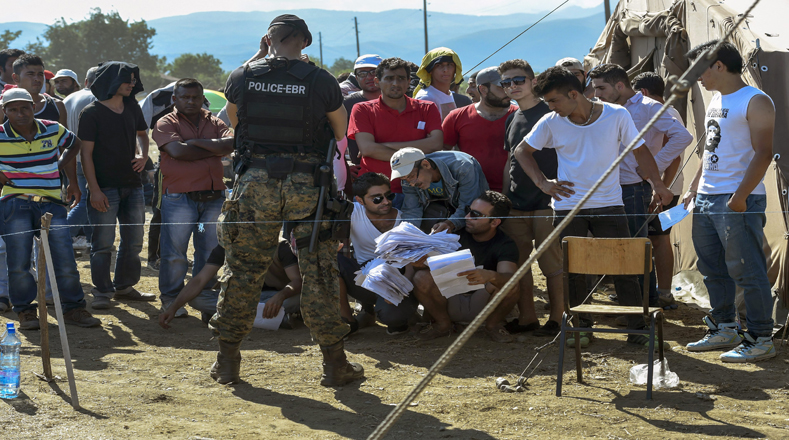 Migrantes aguardan apostados en la frontera a la espera de que las autoridades les concedan el paso.