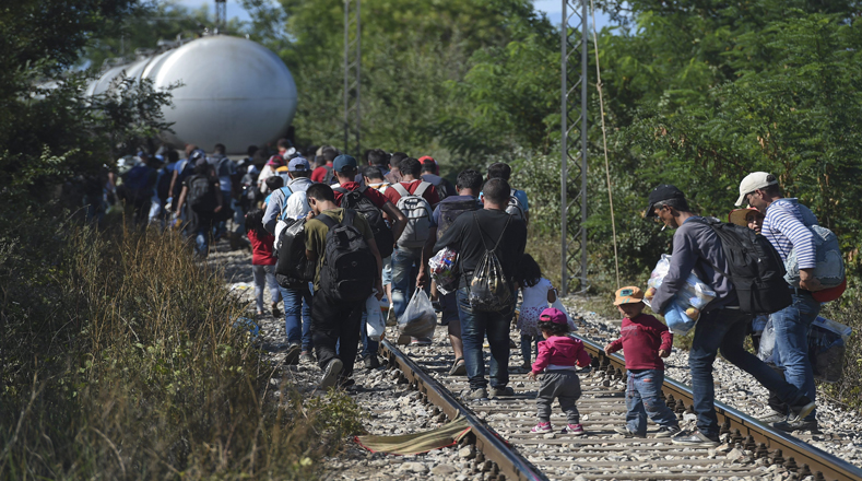 Migrantes camina sobre las vías del tren para coger el tren en dirección a la frontera serbia en la estación de tren en Gevgelija.