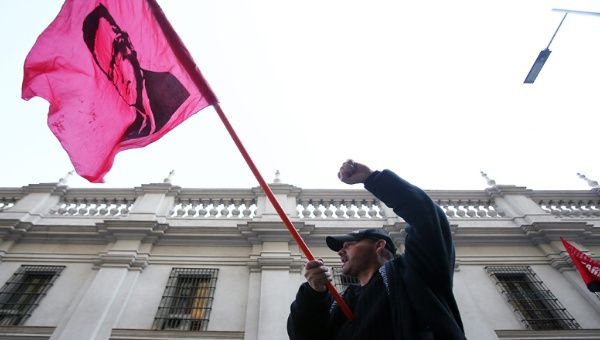 Este hombre alza una bandera con el rostro de Salvador Allende frente al Congreso chileno como símbolo de lealtad al presidente que luchó por liberar a su pueblo del yugo 
