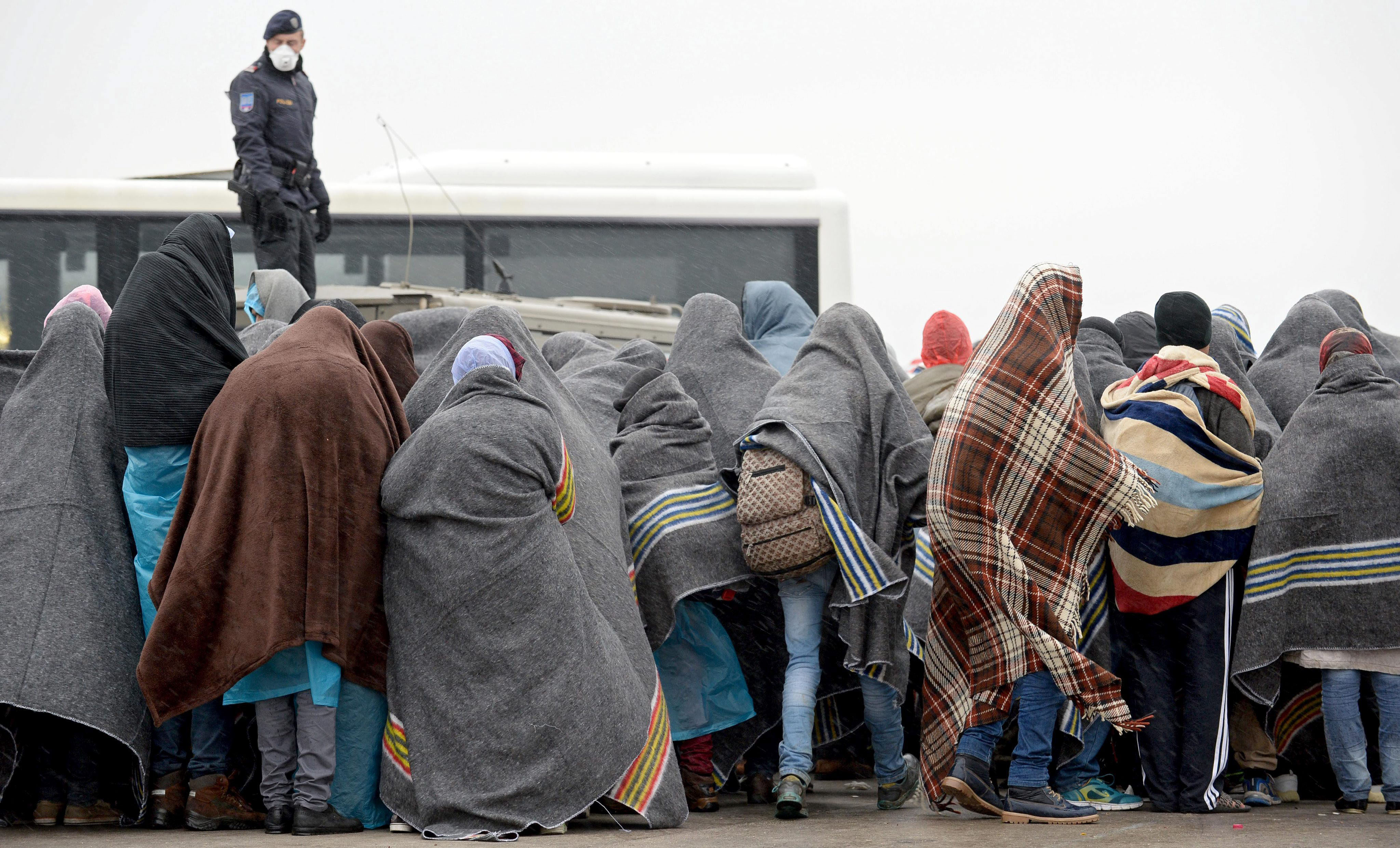 Refugiados esperan bajo la lluvia en un aparcamiento para ser trasladados en la ciudad austriaca de Nickelsdorf, en la frontera con Hungría.
