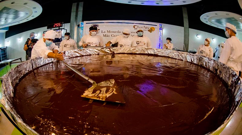 Un grupo de cocineros manipula chocolate durante la elaboración de la moneda de chocolate más grande del mundo.