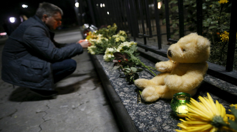 Un hombre enciende una vela a las víctimas de un avión ruso que se estrelló en Egipto , en la embajada rusa en Kiev, Ucrania.