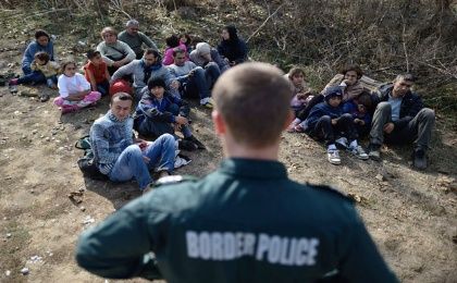 Un policía fronterizo de Bulgaria vigila a un grupo de refugiados sirios, en la frontera entre Turquía y Bulgaria.
