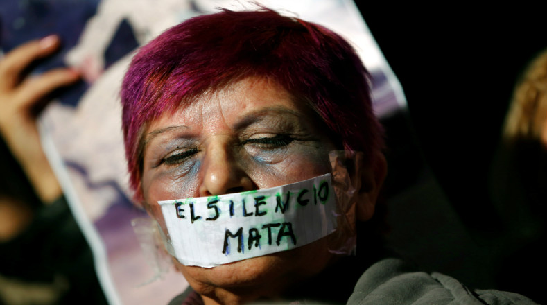 La mujer tiene cinta que cubre su boca con las palabras "El silencio mata" para no ocultar la violencia contra las mujeres.