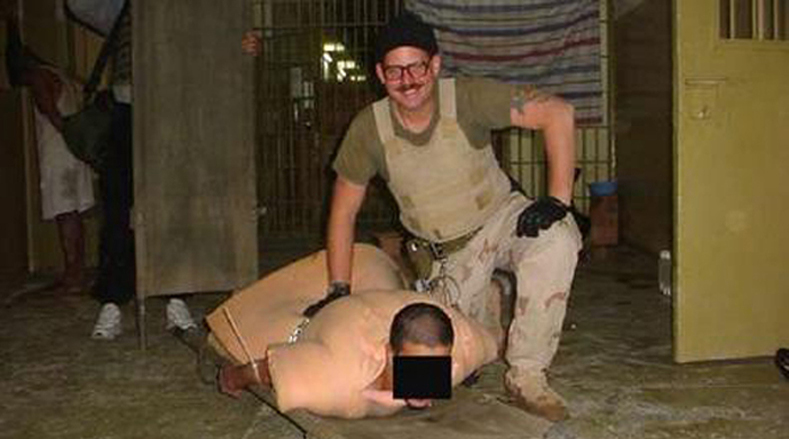 Sgt. Charles Graner posing with a stripped and humiliated detainee.