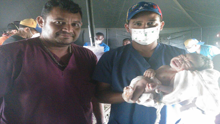 Médicos venezolanos cargan a la criatura recién nacida.