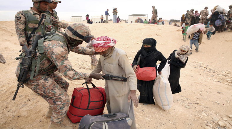 Soldados jordanos cachean a refugiados sirios a su llegada al campamento.