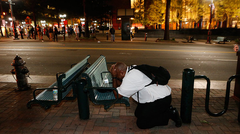 Un hombre llora frente a un banco de la ciudad de Charlotte.