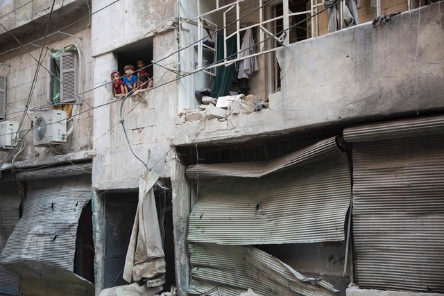 Niños en la ventana de un edificio en ruinas tras los bombardeos en Alepo.