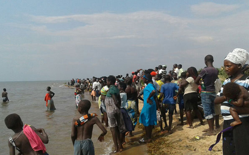 Personas observan a orillas del lago Alberto la recuperación de los cuerpos y el rescate de los sobrevivientes.