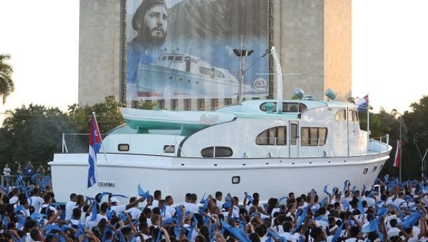 An image of late Cuban President Fidel Castro hangs on a building as a replica of the Granma yacht passes by during a march in Havana, Jan. 2, 2017. 
