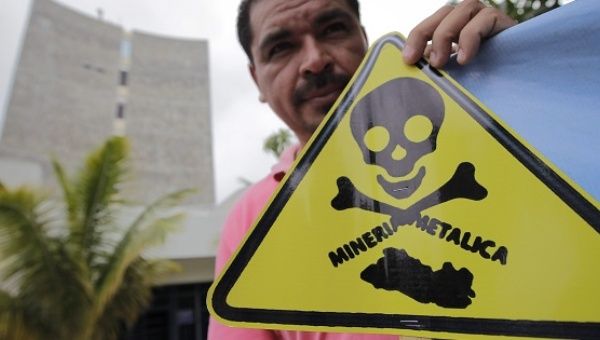 An demonstrator holds a sign condemning the toxicity of metals mining in El Salvador after an anti-mining coalition presented a proposal to block mining in 2013.