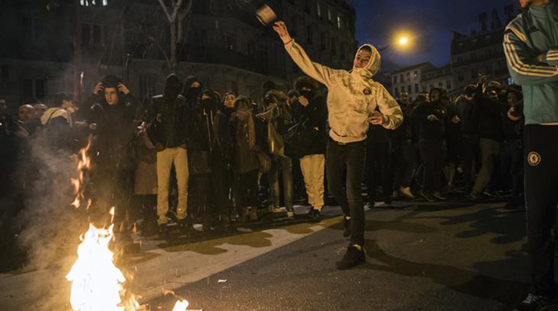 Un manifestante lanza una lata de pintura hacia los policías durante una manifestación en solidaridad con Théo.