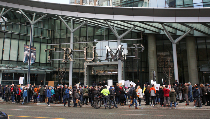 Los manifestantes sostienen pancartas durante la inauguración de la Torre Trump en Vancouver.