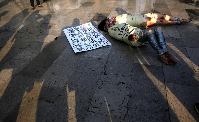 El cartel que reposa sobre el suelo dice: "Nada que ver aquí, solo una víctima más del feminicidio en México. ¡Siga caminando!". 