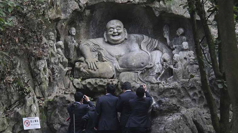 Unos oficinistas frente a una escultura budista del monte