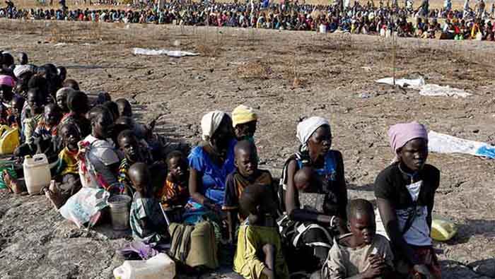 Cientos de mujeres y niños permanecen sentados para obtener provisiones de la ONU.
