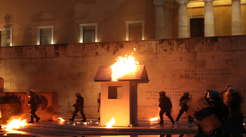 La policía griega lanzó gases lacrimógenos contra los manifestantes fuera del Parlamento en Atenas  donde los legisladores debatieron más recortes de gastos exigidos por los prestamistas internacionales del país a cambio de fondos de rescate..