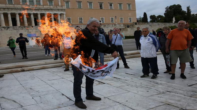 Los manifestantes expresaron su rechazo quemando una bandera del partido de gobierno SYRIZA durante la protesta.