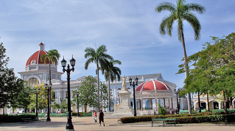Parque Martí, en Cienfuegos, Cuba. Al fondo, a la izquierda, el Palacio de Gobierno (con su espléndida cúpula roja), sede de la Asamblea Provincial del Poder Popular; y a su lado, el Museo Provincial, antigua sede del Casino Español.