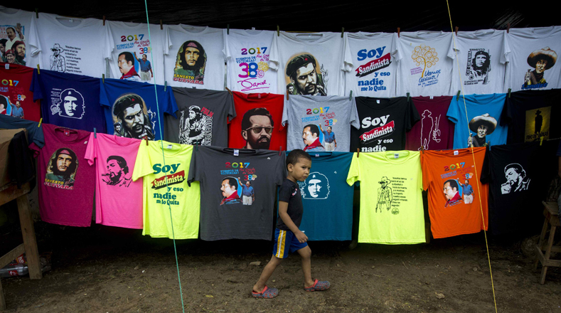 Un niño nicaragüense camina frente a una venta improvisada de camisetas con diseños alusivos a personajes latinoamericanos vinculados a la Revolución Sandinista.