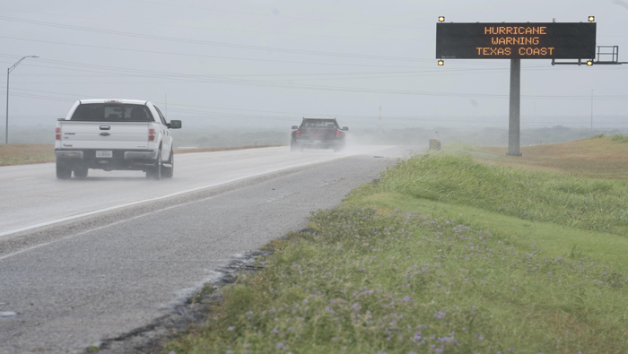 Vehículos circulan hacia el sur por la autopista interestatal 37 junto a un cartel comercial que avisa de las malas condiciones meteorológicas en Corpus Christi, Texas, Estados Unidos.