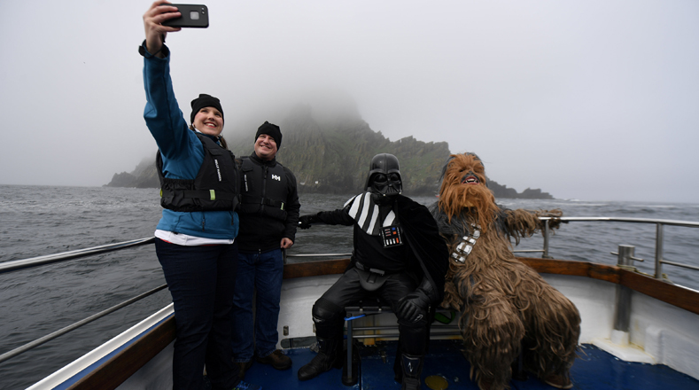 Darth Vader y Chewbacca disfrutan de un viaje en barco a la isla Skellig, Irlanda, durante el festival inaugural "May The 4th Be With You", mientras los turistas se toman autofotos con ellos. 