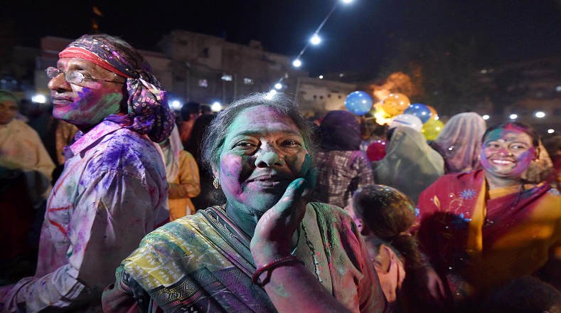 En la víspera de Holi, devotos adultos y niños celebran rociando soluciones en polvo de colores en el aire, y untándose las caras unos a otros.