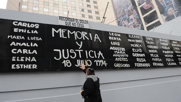 Un hombre toca un cartel con el nombre de las víctimas del atentado terrorista del 18 de julio de 1994.
